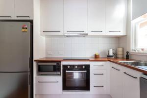 une cuisine avec des armoires blanches et un réfrigérateur en acier inoxydable dans l'établissement Victoria Cottage, à Ulverstone