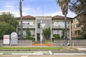 an apartment building with palm trees in front of it at Charming 1-Bed with Fireplace by the Beach in Melbourne