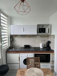 a kitchen with a table and a sink and a microwave at Appartement Nature et Mer in Sainte-Anne