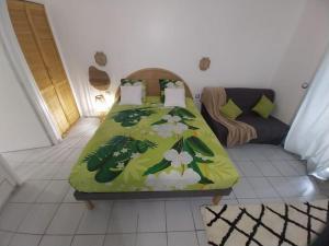 a bedroom with a bed with a green blanket with flowers at Appartement Nature et Mer in Sainte-Anne