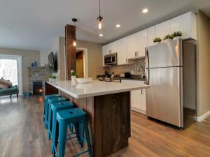 a kitchen with a stainless steel refrigerator and blue stools at Modern Killington Farmhouse Condo - Killington Center 412 in Killington