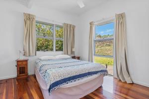 a white bedroom with a bed and two windows at DOLCE VILLA in Tangalooma