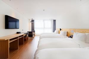 a hotel room with three beds and a flat screen tv at 그랜드 모먼트 in Busan