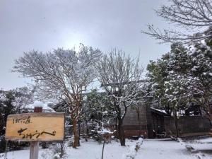 a sign in the snow in front of a house at はたご屋ちゅうべ in Taki
