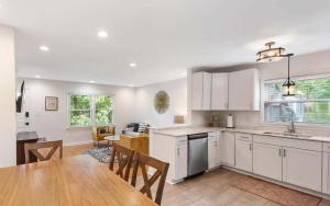 a kitchen with white cabinets and a wooden table at Charming 4-Bed Home with Modern Touches & Porch in Louisville