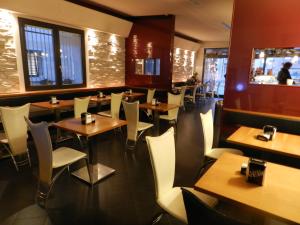 a restaurant with wooden tables and white chairs at Locanda Trattoria Caffè Cavour in Cittadella
