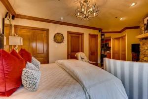 a bedroom with a bed with red pillows and a chandelier at McCoy Peak 201 by East West Hospitality in Beaver Creek