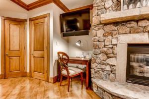a room with a stone fireplace with a desk and a chair at McCoy Peak 201 by East West Hospitality in Beaver Creek
