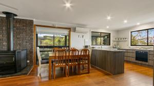 cocina con mesa, sillas y chimenea en Anchored on Capes Upstairs, en Lakes Entrance