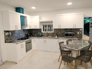 Una cocina con gabinetes blancos y una mesa y sillas. en Agréable appartement en rooftop, en La Cabirma