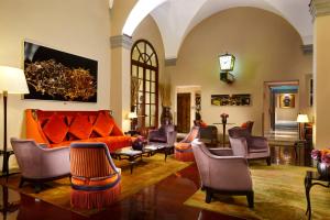 Hotel L'Orologio - WTB Hotels في فلورنسا: غرفة معيشة مع أريكة برتقالية وكراسي