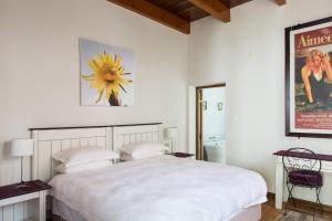 una camera da letto con un grande letto bianco e una foto di 22 Van Wijk Street Tourist Accommodation a Franschhoek
