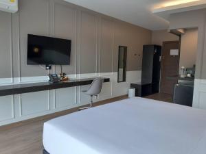 甘烹碧J2 Hotel的一间卧室配有一张床、一台电视和一把椅子