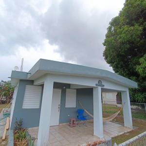 Una pequeña casa azul con una hamaca. en Casa completa, privada con piscina, en Maunabo