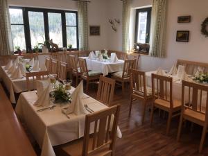 ein Restaurant mit Tischen und Stühlen sowie weißen Tischdecken in der Unterkunft Berghotel Mooshütte in Lohberg