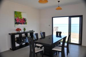 a dining room with a table and chairs and the ocean at Villas Vetiver in Rodrigues Island