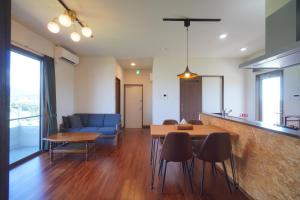 a living room with a table and a blue couch at CondoYumangi in Onna +51 photos