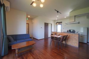 a living room with a blue couch and a table at CondoYumangi in Onna