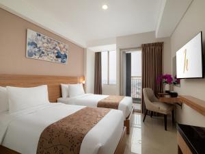 a hotel room with two beds and a desk at Horison Suite & Residences Iswara Bekasi in Rawapanjang