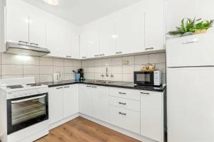 a white kitchen with white cabinets and a refrigerator at Spacious 1-Bedroom Apartment with Car Space in Melbourne