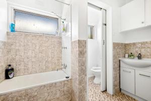 a bathroom with a tub and a toilet and a sink at Spacious 1-Bedroom Apartment with Car Space in Melbourne