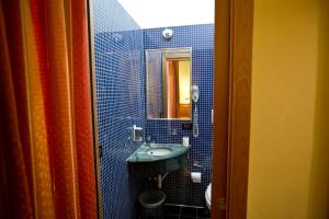 bagno piastrellato blu con lavandino e specchio di Hotel Lella a Roma