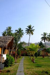 a path in front of a house with palm trees at Blue Sky Cottages Hampi in Hampi +20 photos