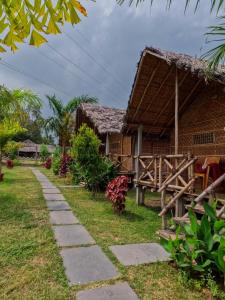 a house with a thatched roof and a path at Blue Sky Cottages Hampi in Hampi