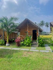 a small wooden house with a door and a palm tree at Blue Sky Cottages Hampi in Hampi