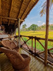 a porch with wicker chairs and a view of a field at Blue Sky Cottages Hampi in Hampi
