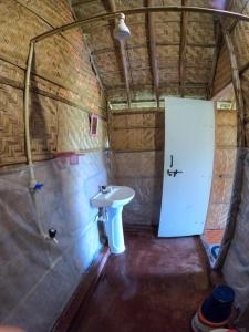 a bathroom with a white sink and a door at Blue Sky Cottages Hampi in Hampi