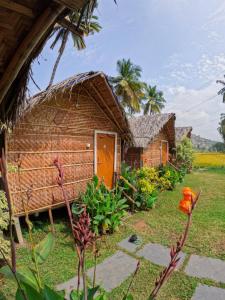 a small house with an orange door in a yard at Blue Sky Cottages Hampi in Hampi