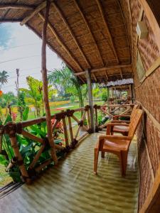 a porch of a resort with chairs and tables at Blue Sky Cottages Hampi in Hampi