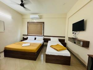 a hotel room with two beds and a flat screen tv at DREAMZ LUXURY HOMe in Kammasandra