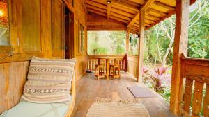 a porch of a wooden house with a table and chairs at Rumah Bambu Gladek Tiga in Uluwatu