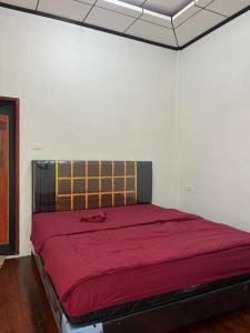 a bed in a white room with a red blanket at Para para cafe & cottage in Berastagi +5 photos