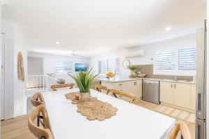 Una cocina y un comedor con una mesa y sillas blancas. en Hanks Corlette House, 49 Pantowora St - pet friendly, air con, boat parking, Wi-Fi, en Corlette