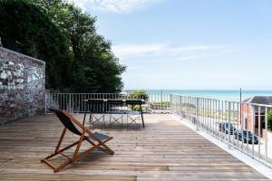 a wooden deck with a table and a chair at Les Ailes du moulin in Ault