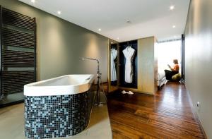 a bathroom with a tub and a man sitting in a room at Le Petit Létraz in Duingt
