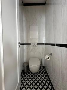 a bathroom with a toilet and a black and white tile floor at Rezidencia OPERA - Villa Bizet in Turčianske Teplice