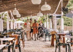 three people walking through a restaurant with tables and chairs at Hard Rock Hotel Ibiza in Playa d'en Bossa