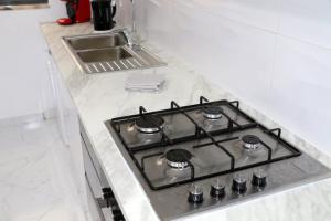 a stove top in a white kitchen with a sink at Figo Apartamentos Cidadela Comfort Flats in Praia +2 photos