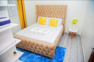 a small bedroom with a large bed with yellow pillows at Kezmo Paradise in Mombasa