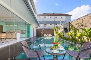 Un balcón con mesa y sillas y una piscina. en Nayana 4 BR Private Pool Villa ZN222, en Legian