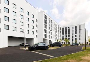 a white building with two cars parked in a parking lot at B&B HOTEL Paris Clichy-sous-Bois 3 étoiles in Clichy-sous-Bois