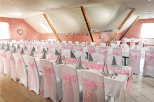 a room with rows of white chairs with pink bows at Penzion Pivovar Vraník in Trnava