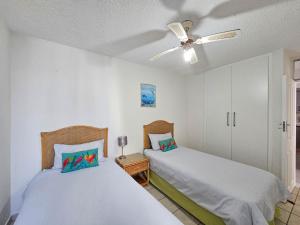 a bedroom with two beds and a ceiling fan at Beachcombers 13 in Ballito