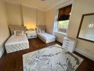 a bedroom with two beds and a window and a rug at 3 Bed - Sleeps 7 - Free Parking - Central Location in Glasgow