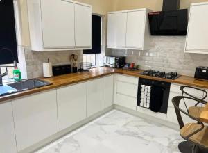 a white kitchen with white cabinets and a sink at 3 Bed - Sleeps 7 - Free Parking - Central Location in Glasgow