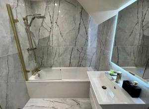 a bathroom with a white tub and a sink at 3 Bed - Sleeps 7 - Free Parking - Central Location in Glasgow